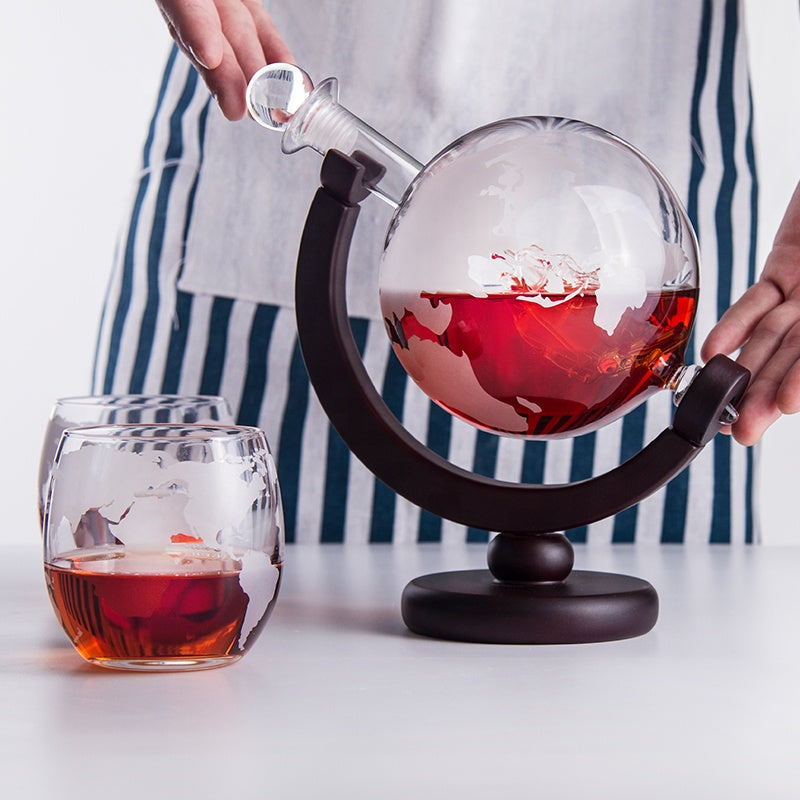 Elegant globe whiskey decanter set including decanter, wooden stand, and 2 glasses.